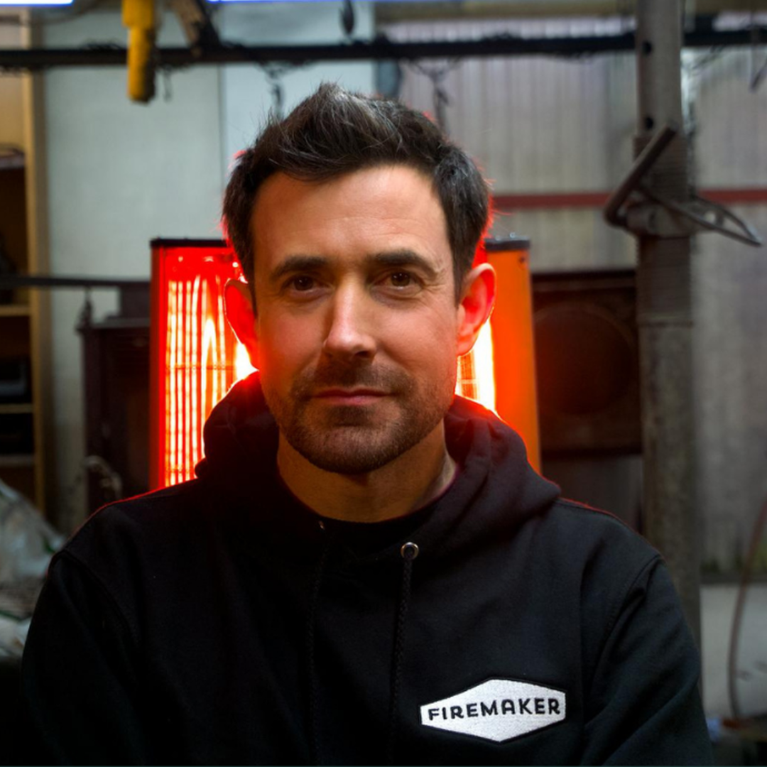 James headshot taken in the Firemaker workshop in front of a glowing heater