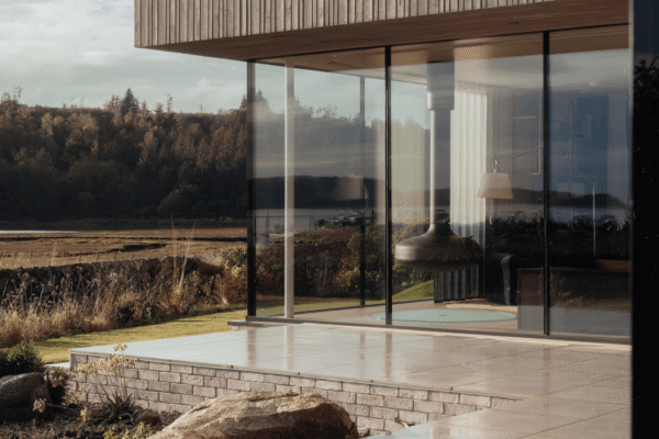 Tidal House lounge taken from the exterior, modern stunning building with large windows looking into the lounge with the FireBob in the lounge.