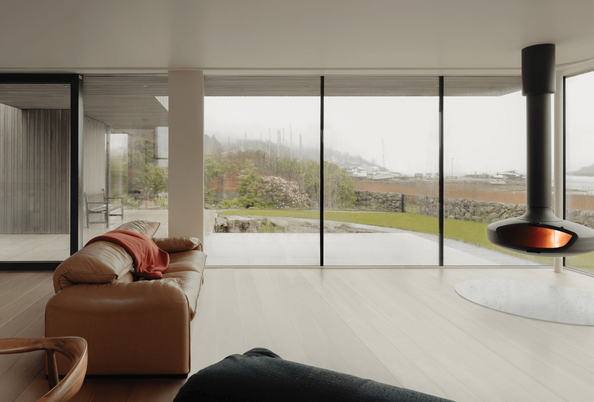 Interior of Tidal House lounge area, with large floor to ceiling windows and the FireBob fireplace taking centre place.