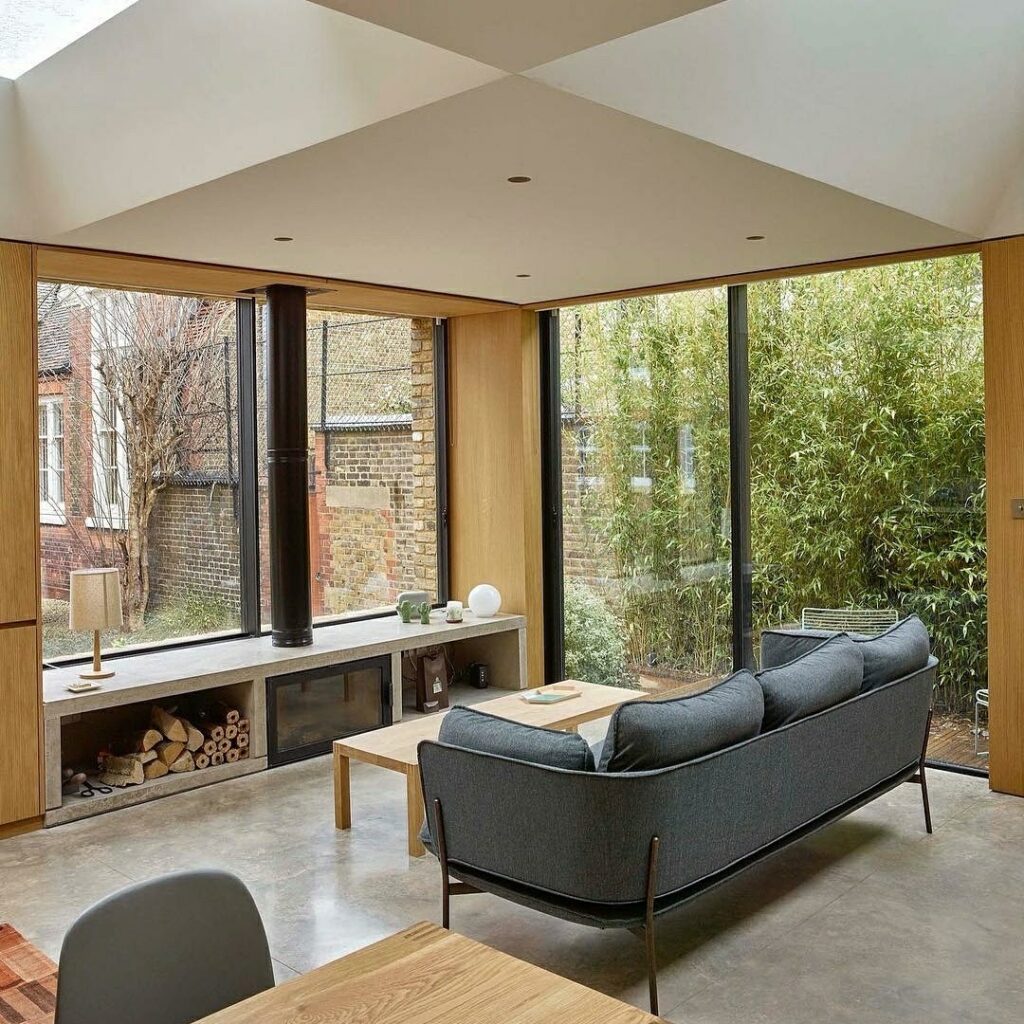 Contemporary interior. Calm, modern aesthetic. Blue soap in front of fireplace. Big open window.