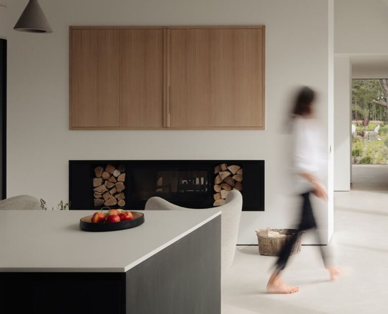 Woman walking through a contemporary home. The modern interior features clean lines, natural light and a warm, inviting atmosphere.