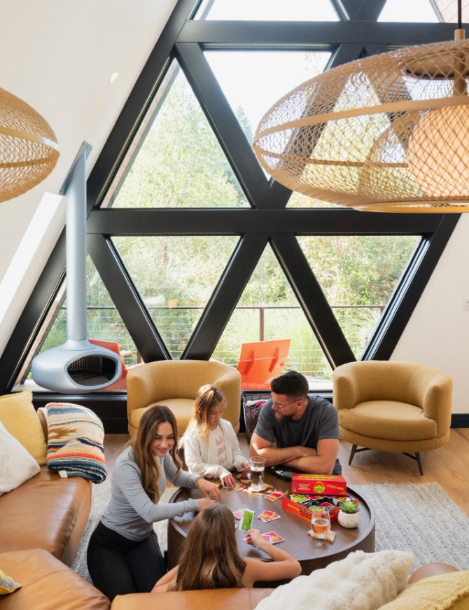 Suspended BioBob bioethanol fireplace in a contemporary living room surrounded by indoor plants. The handcrafted ceiling mounted fireplace creates a warm focal point, complementing the natural greenery and modern interior with a calm, inviting atmosphere.